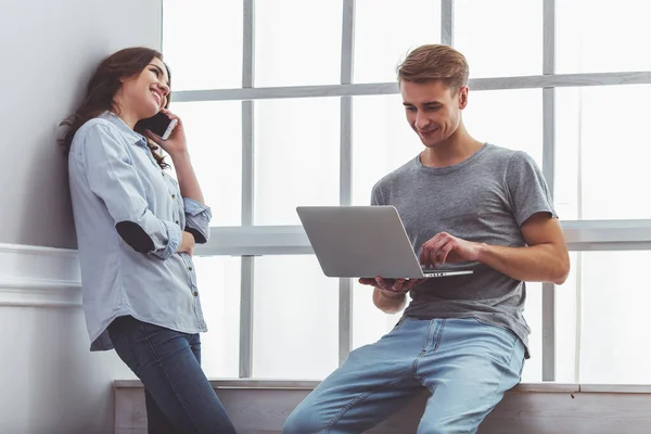 Szczęśliwa Para Używa Laptopa Rozmawia Przez Telefon Stojąc Pobliżu Parapety — Zdjęcie stockowe