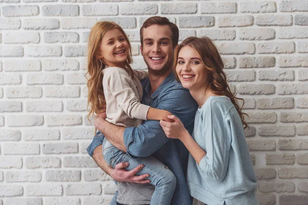 Hermosa Familia Joven Abrazándose Mirando Cámara Sonriendo Mientras Está Pie —  Fotos de Stock