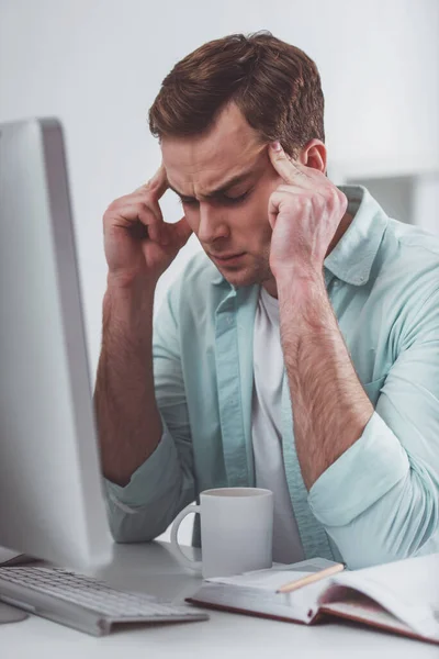 オフィスで働いている間頭痛を持つカジュアルな服の若い魅力的なビジネスマン — ストック写真