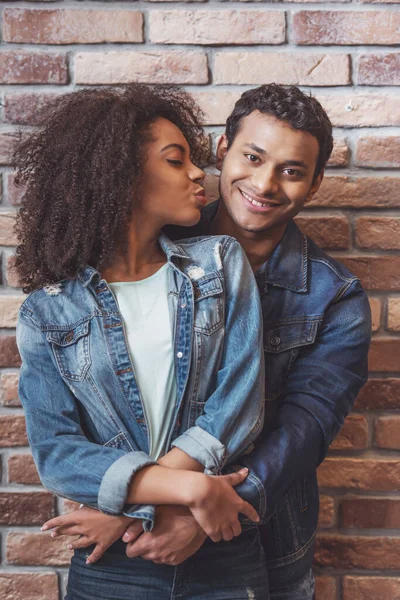 年轻迷人的非洲裔美国夫妇靠着砖墙背靠背地拥抱在一起 女人亲吻男人 — 图库照片