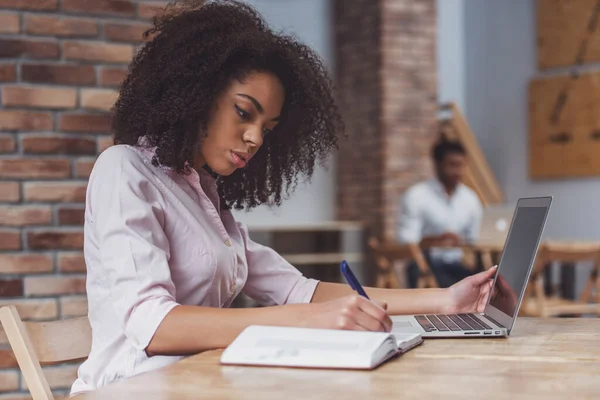 Junge Schöne Afroamerikanische Geschäftsfrau Benutzt Laptop Und Schreibt Notizbuch Während — Stockfoto