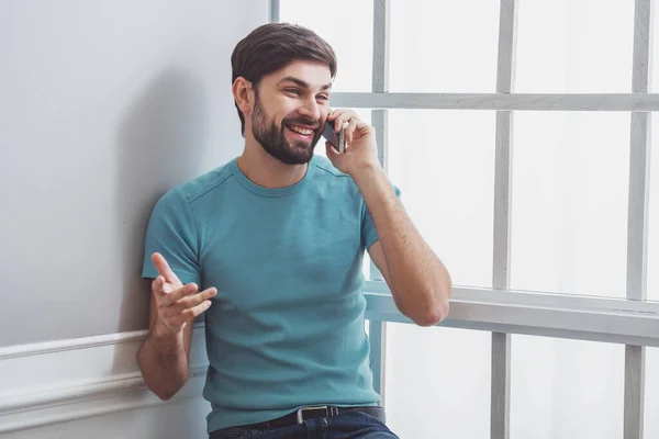 Przystojny Mężczyzna Ubranie Rozmowy Telefon Komórkowy Uśmiechając Się Siedząc Pobliżu — Zdjęcie stockowe