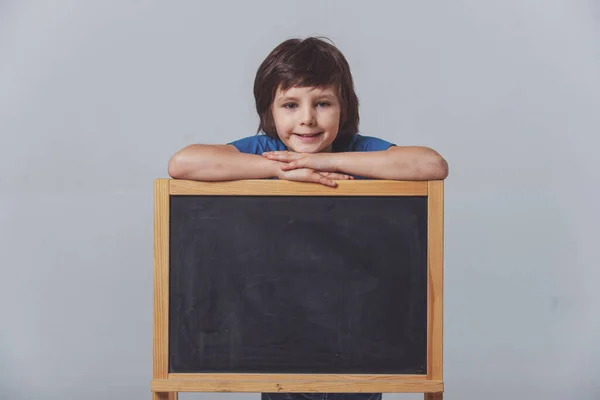 Schattige Kleine Jongen Een Blauw Shirt Leunend Een Schoolbord Kijken — Stockfoto