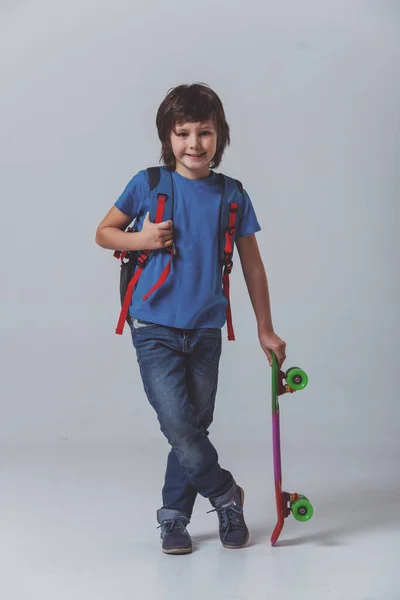 Menino Bonito Uma Camiseta Azul Com Uma Mochila Segurando Skate — Fotografia de Stock