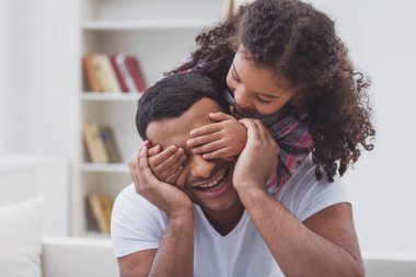 Sevimli küçük Afro-Amerikan kız baba gözlerini kapsayan rahat kıyafetler içinde. Her iki gülümseyen.