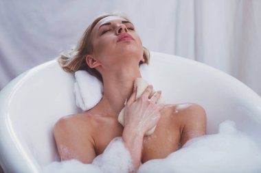 Kapalı gözlerle yalan yıkama, küçük bir sak kullanarak ve köpük, keyifli banyo keyfi güzel genç kadın