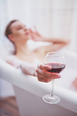 Bir kadeh şarap, tutan köpük, keyifli banyo keyfi güzel genç kadın el ile cam odaklı