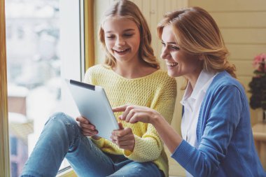 Güzel genç kız ve tablet kullanma ve gülümseyen güzel annesi