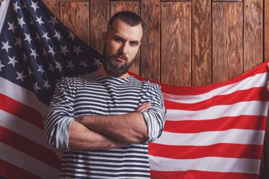 Çizgili yelek sakallı şık adam kamera bakarak, Amerikan bayrağı ile ahşap bir arka plan üzerinde duran