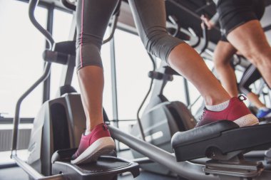 Gençlerin spor salonunda eliptik bir eğitmen olarak çalışma dışarı çekici arkadan görünüm