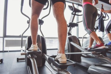 Gençlerin spor salonunda eliptik bir eğitmen olarak çalışma dışarı çekici arkadan görünüm