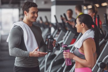 Çekici genç insanlar içme suyu, söz ve spor salonunda dururken gülümseyen