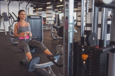 Spor salonu fitness merkezinde egzersiz, demir pompalama ve gülümseyen çekici genç kadın