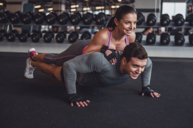 Gönderme yapan çekici genç kaslı erkek ups spor salonunda, kadın ona yalan. Her iki gülümseyen
