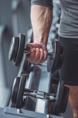 Yakışıklı genç kaslı adam spor salonunda, dumbell ile çalışma dışarı yakın çekim
