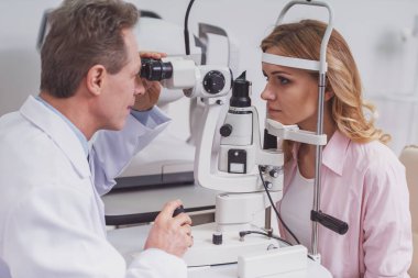 Güzel kadının gözleri modern ekipmanları ile inceleyerek yakışıklı göz doktoru