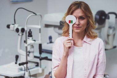 Bir göz kapsayan ve onu görme keskinliği kontrol göz doktoruna üzerinde istişare, genç güzel kadın