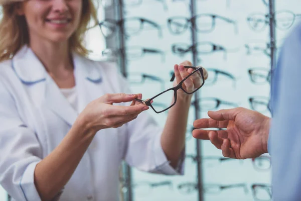 ハンサムな中年の人相談に眼科医で 眼鏡を提供する若い美しい女性医師 — ストック写真