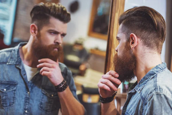 Bonito Barbeiro Barbudo Jovem Olhando Espelho Ajustando Sua Barba Enquanto — Fotografia de Stock