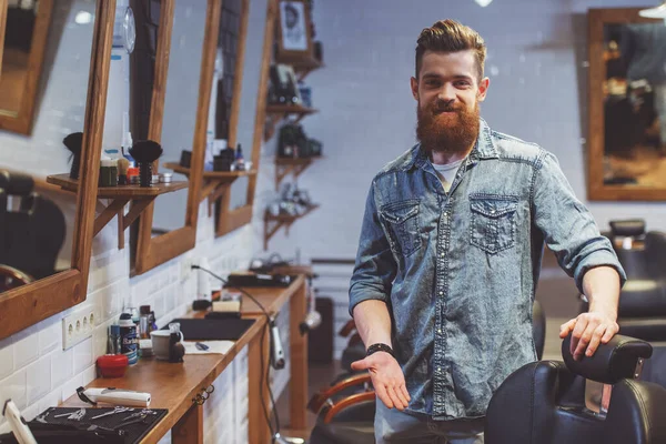 Handsome Young Bearded Barber Pointing Chair Looking Camera Smiling While — Stock Photo, Image