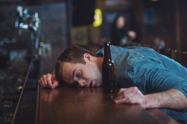 Genç adam rahat kıyafetler içinde bir bar bira şişe Yataklı vagon barda sayaç