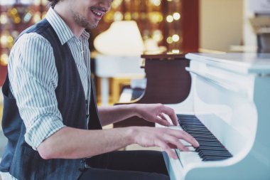 Klasik yelek kırpılmış bir piyano müzik bir dükkanda oynarken gülümseyen yakışıklı şık adam