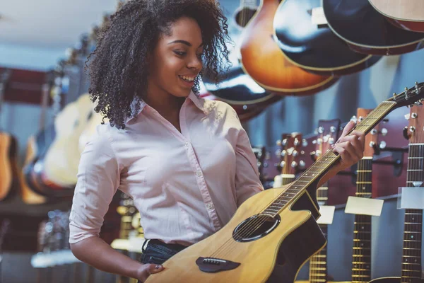 Bir Gitar Tutarak Müzikal Bir Dükkanda Duran Gülümseyen Güzel Afro — Stok fotoğraf