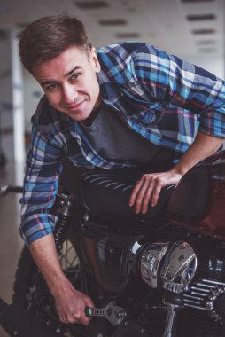 Rahat kıyafetler çekici sarışın adam kameraya bakıyor ve bir motosiklet kısayollarımı gülümseyen