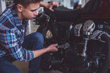 Rahat kıyafetler çekici sarışın adam bir motosiklet tamiri