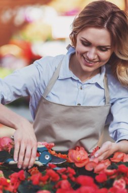 Güzel genç kadın önlük orangery bitkilerde bakmakta iken gülümsüyor
