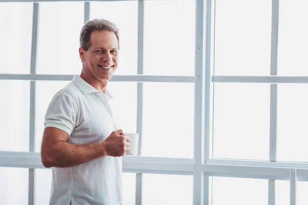 Guapo Hombre Mediana Edad Está Sosteniendo Una Taza Mirando Cámara —  Fotos de Stock