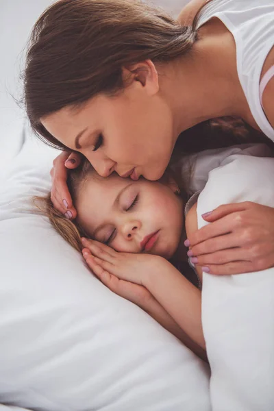 美しい若い母親が眠っているかわいい小さな娘にキス クローズ アップ — ストック写真