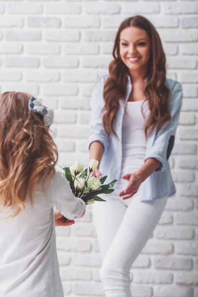 Linda Niña Está Dando Flores Hermosa Madre Joven Contra Pared — Foto de Stock