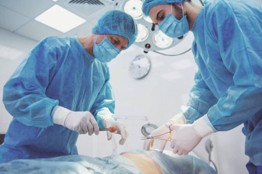 Takım cerrahlar tıp aletleri, modern bir ameliyat odasında kullanarak bir işlem gerçekleştiriyorsunuz