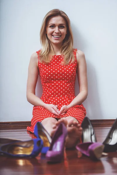 赤いドレスで美しい少女がカメラ目線とドレッシング ルームで高いヒールの靴の中で座って笑顔 — ストック写真