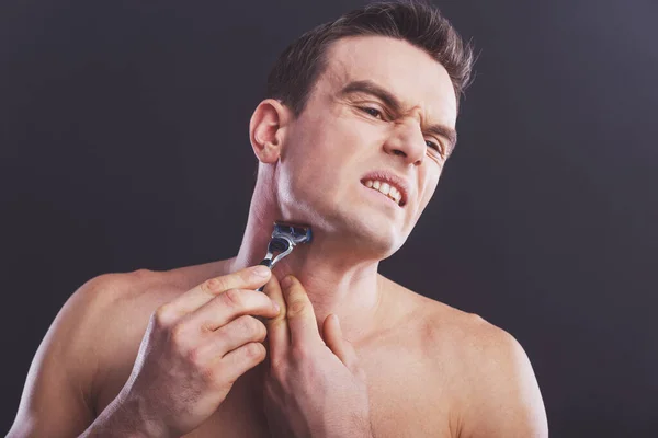 英俊的裸体男人受伤刮脸时用一把剃须刀 在深色背景上的肖像 — 图库照片