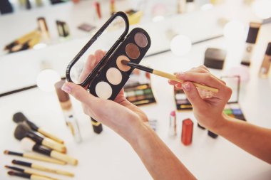 Göz farı makyaj yaparken tutan güzel genç kadın kırpılmış görüntü