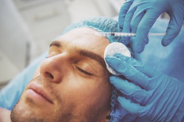 Yakışıklı genç bir enjeksiyon almak yüzüne, gözler, yakın çekim kapalı ile yalan