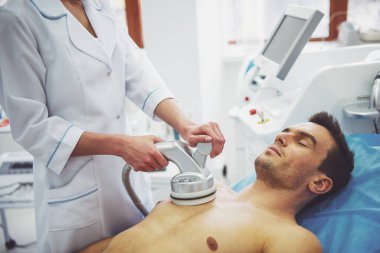 Yakışıklı adam cilt tedavi olmaya başladı. Kadın doktor modern ekipman kullanarak yordamı taahhüt