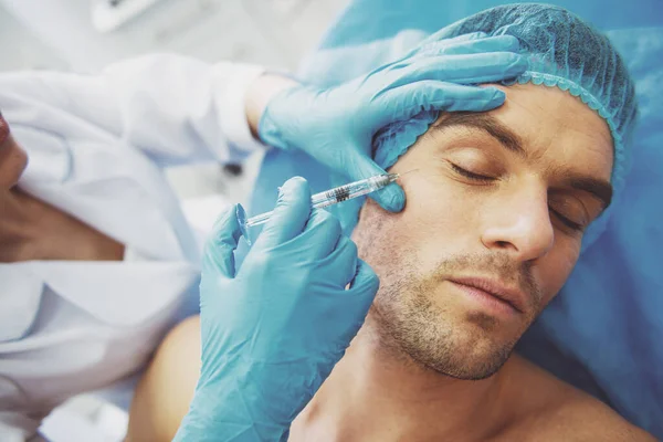 Kapalı gözlerle yalan yüz içinde bir enjeksiyon almak yakışıklı genç adam portresi