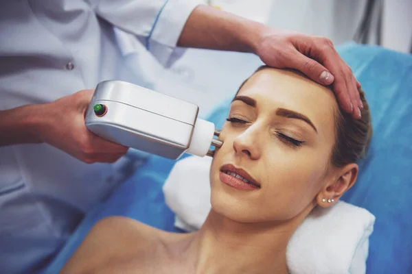 美丽的女人正在脸上的皮肤治疗 医生正在采用一种现代设备的程序 — 图库照片