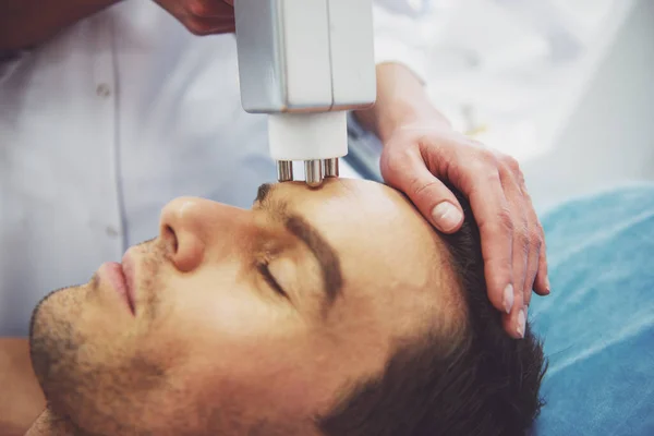 英俊的男人正在脸上的皮肤治疗 医生正在使用现代化的设备 特写的程序 — 图库照片