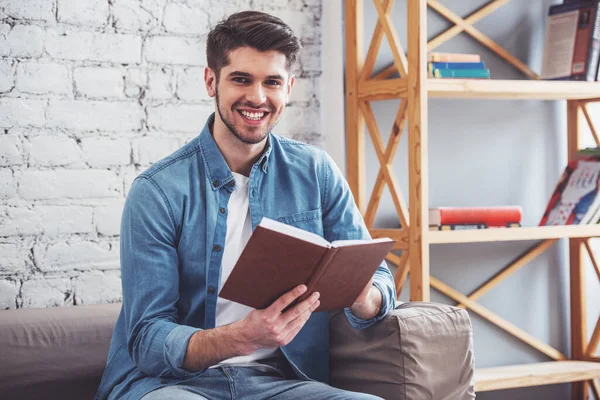 Joven Atractivo Está Leyendo Libro Mirando Cámara Sonriendo Mientras Está —  Fotos de Stock