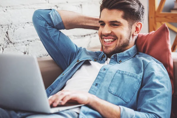 Joven Atractivo Está Utilizando Ordenador Portátil Sonriendo Mientras Está Acostado —  Fotos de Stock