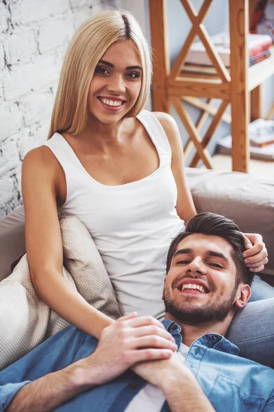 Hermosa Pareja Joven Está Mirando Cámara Sonriendo Mientras Sienta Sofá — Foto de Stock