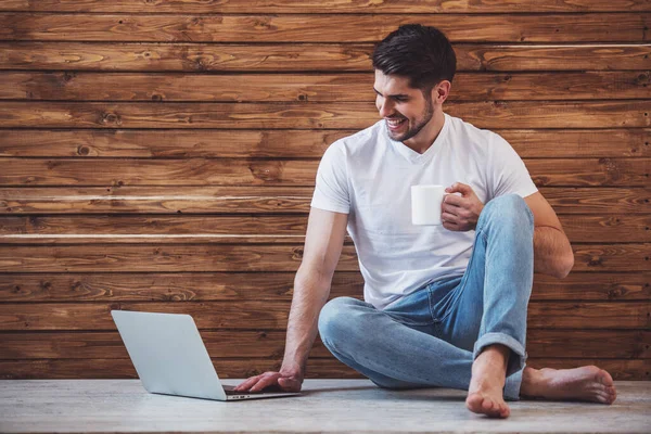 Schöner Junger Mann Benutzt Einen Laptop Hält Einen Becher Mit — Stockfoto