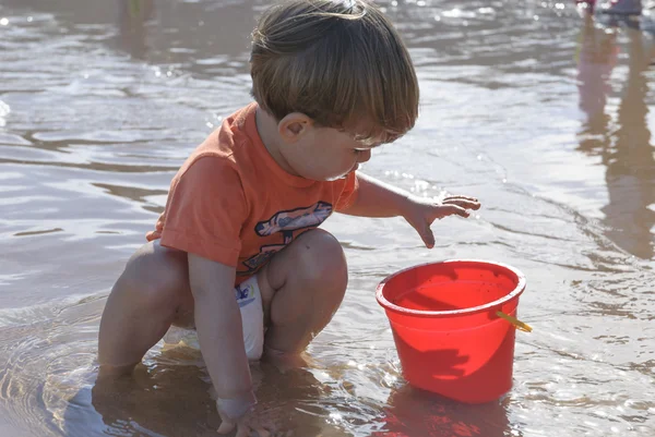 Petit enfant jouant sur la plage avec seau rouge — Photo