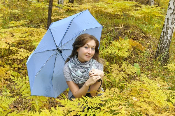 Beautiful woman in autumn forest with blue umbrella — Stock Photo, Image