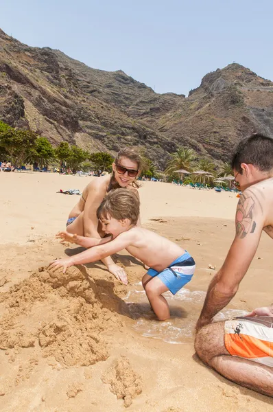 Famille heureuse jouant sur la plage — Photo