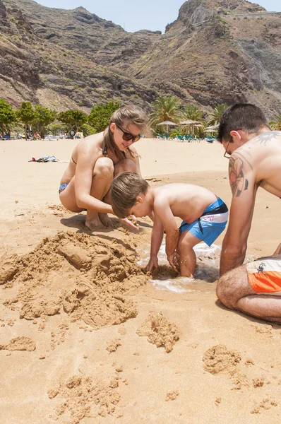 Família feliz jogando na praia — Fotografia de Stock